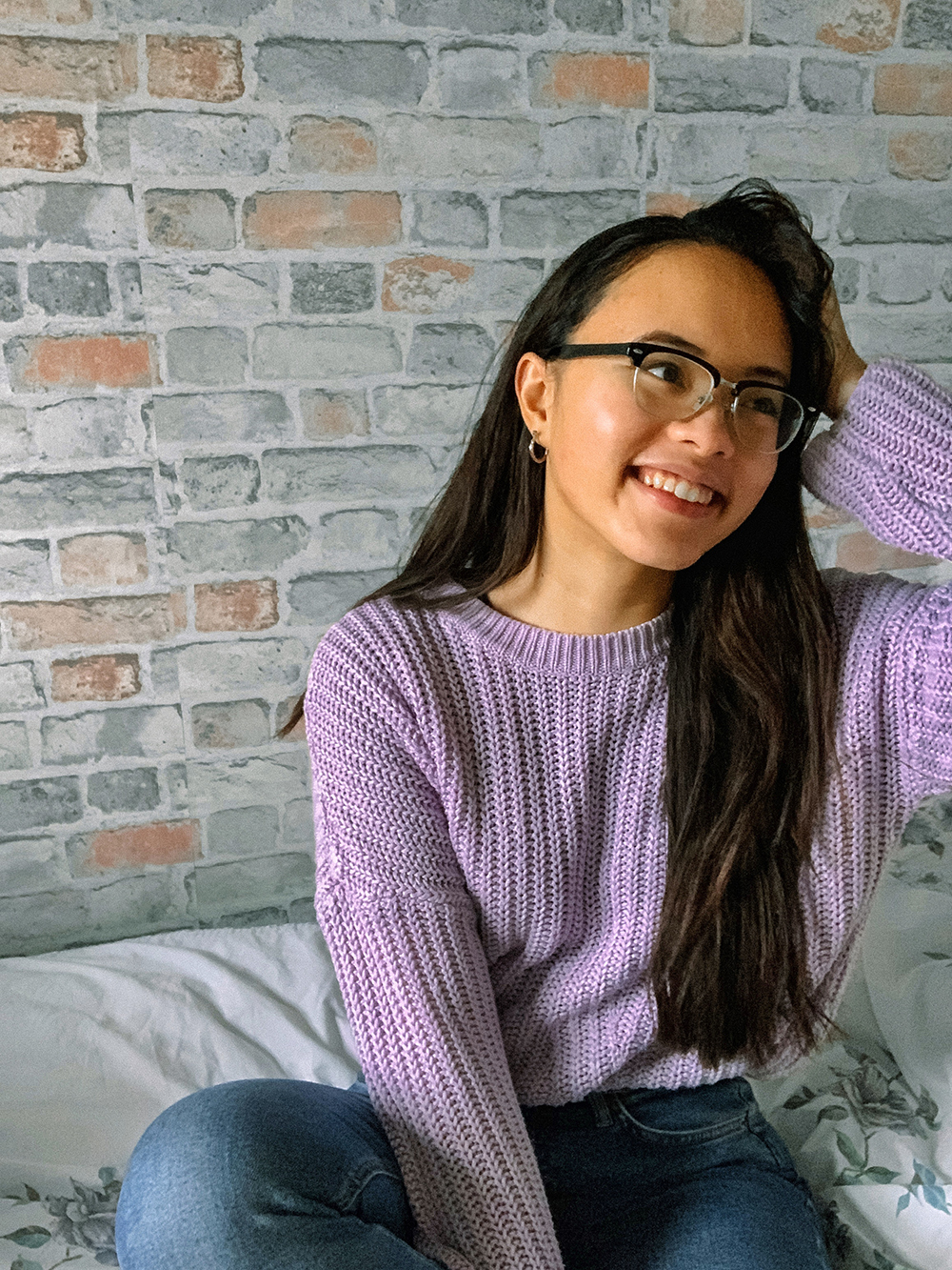 Pauline sitting down, wearing a purple jumper, looking away.