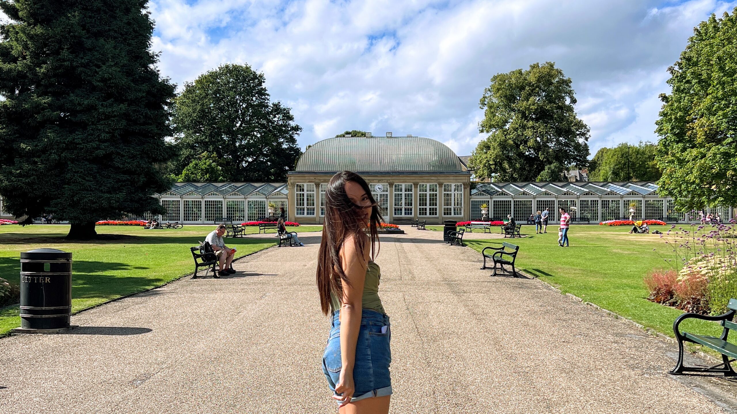 Pauline with the wind blowing her hair on her face, wearing a green top and blue shorts.