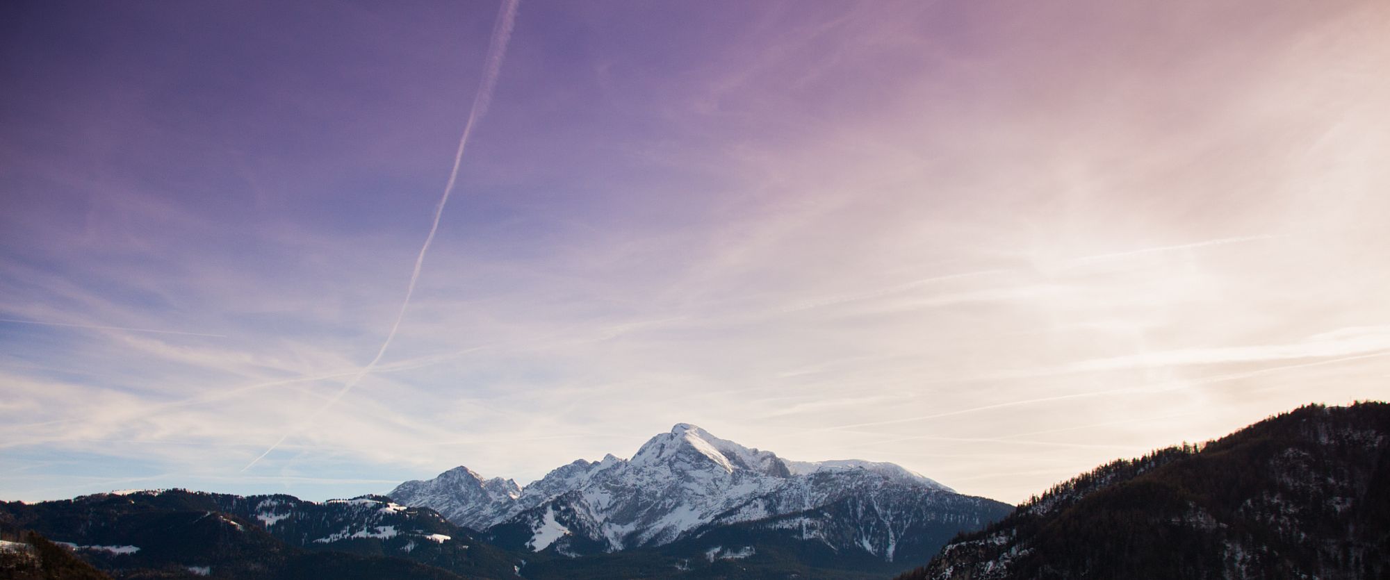 Snow-covered mountain peaks under a pastel sky at sunset
